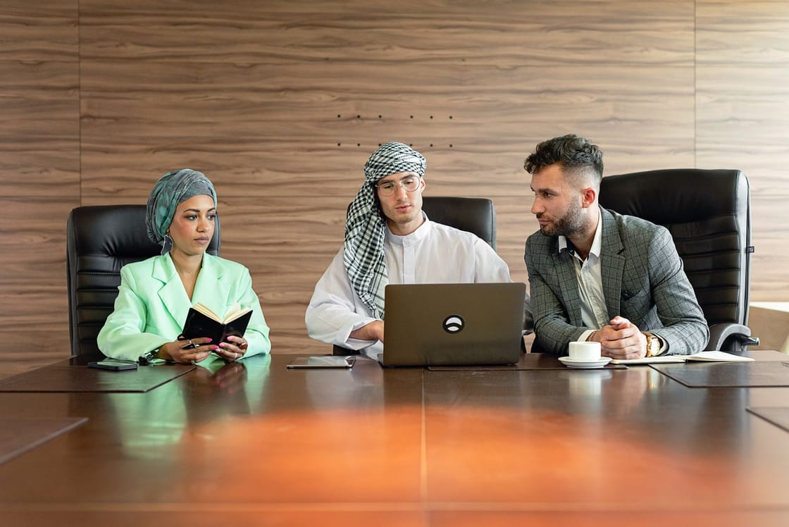Drei Personen besprechen gemeinsam ein Vorhaben mit Laptop und Notizen