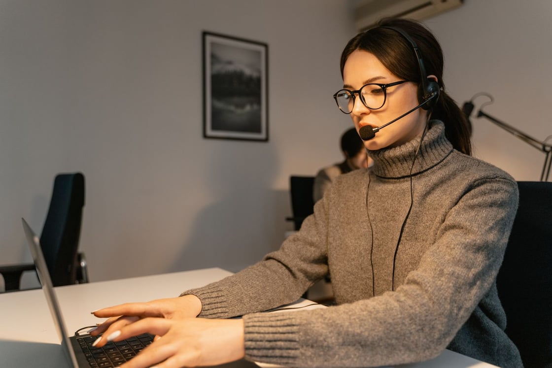 Una mujer con auriculares conversa frente a su portátil