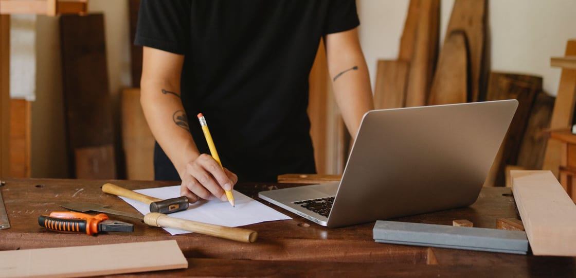 Eine Person plant mit Laptop und Notizen ein Vorhaben an einem Arbeitsplatz