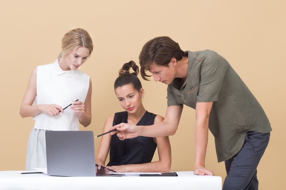 Three people discussing their work together at a laptop