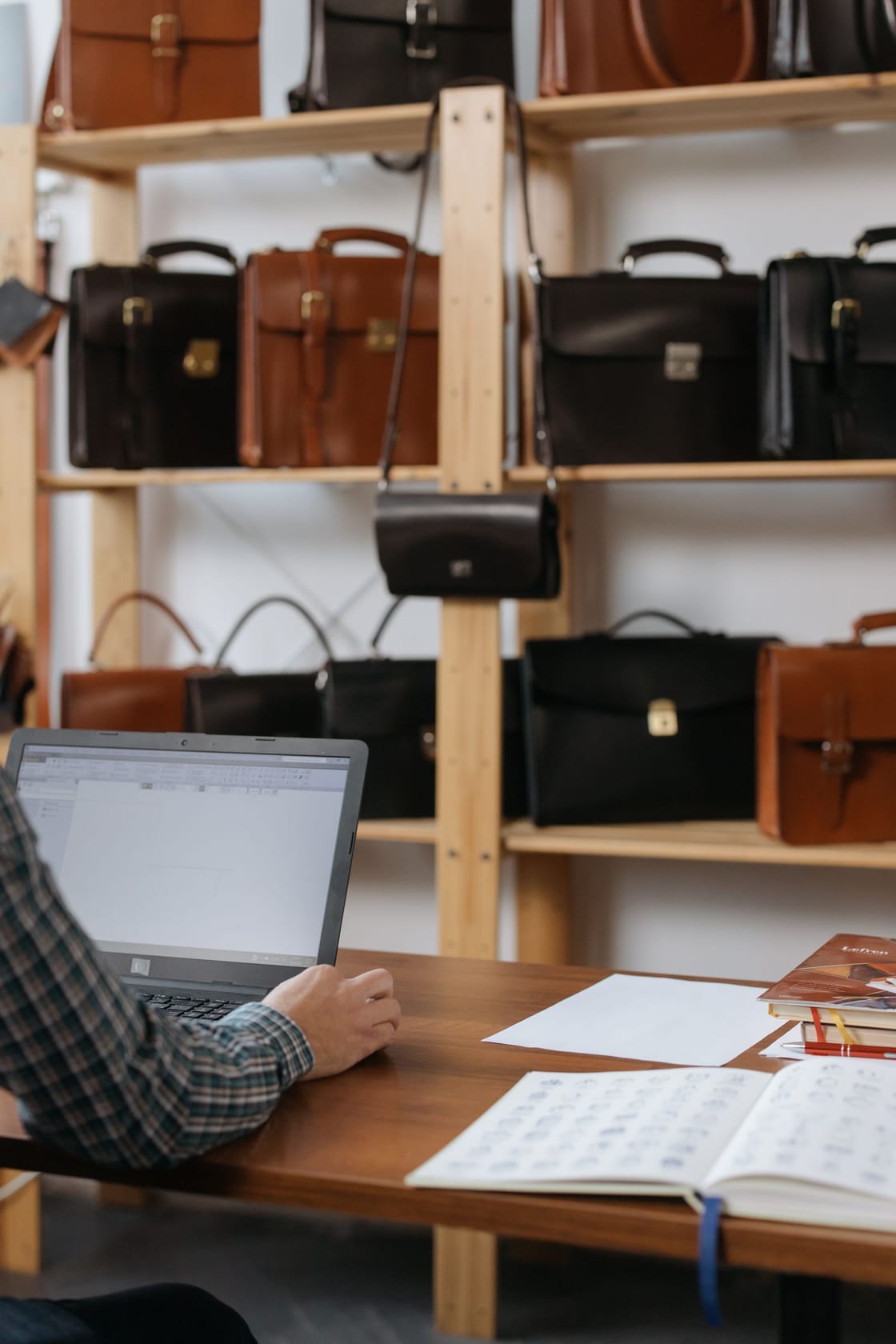 A retailer working on a laptop in a leather bag store