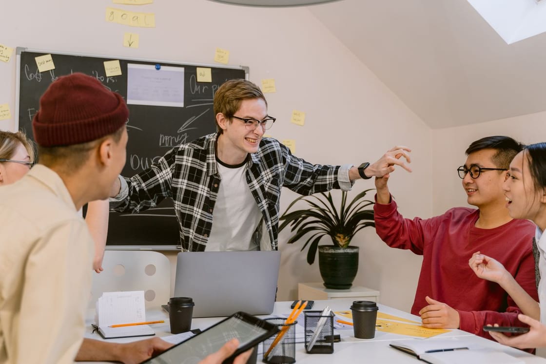 Un equipo comparte ideas en una mesa con portátiles.